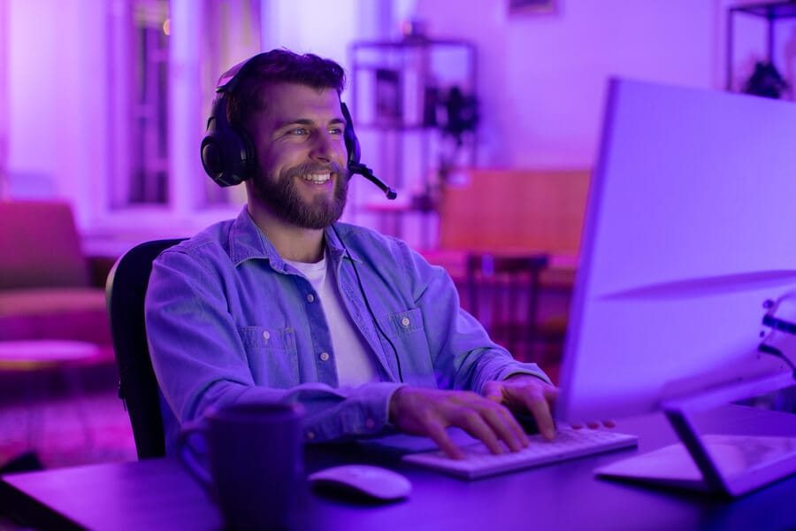 Crawl budget conclusiones - Hombre con auriculares trabajando frente a un computador en un ambiente iluminado con luces de neón.