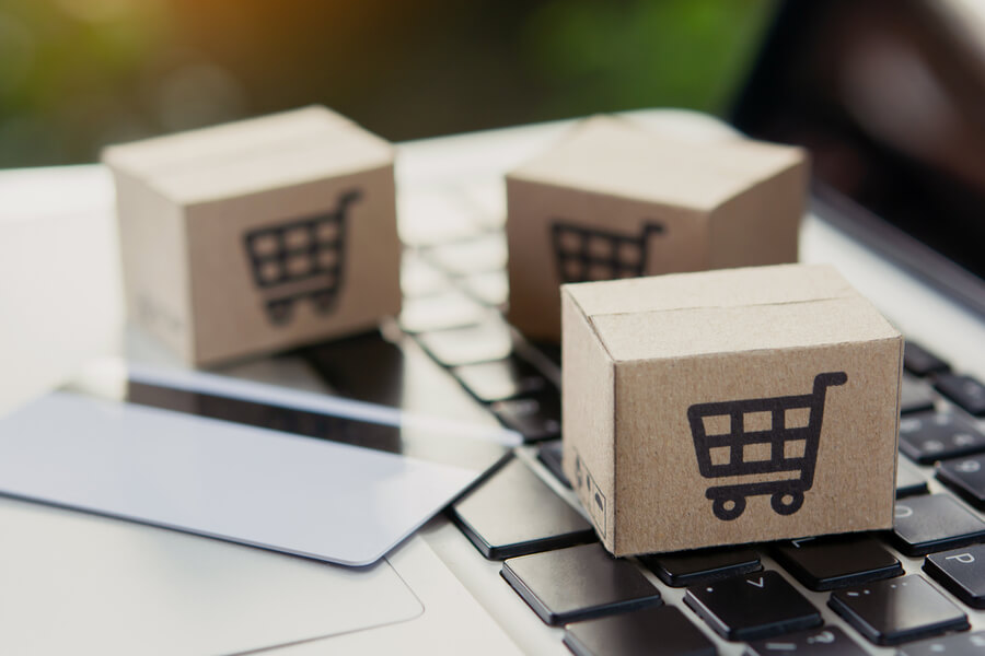 Caso de éxito Mundo Fit - Ecommerce packages with shopping cart icons on a laptop keyboard.